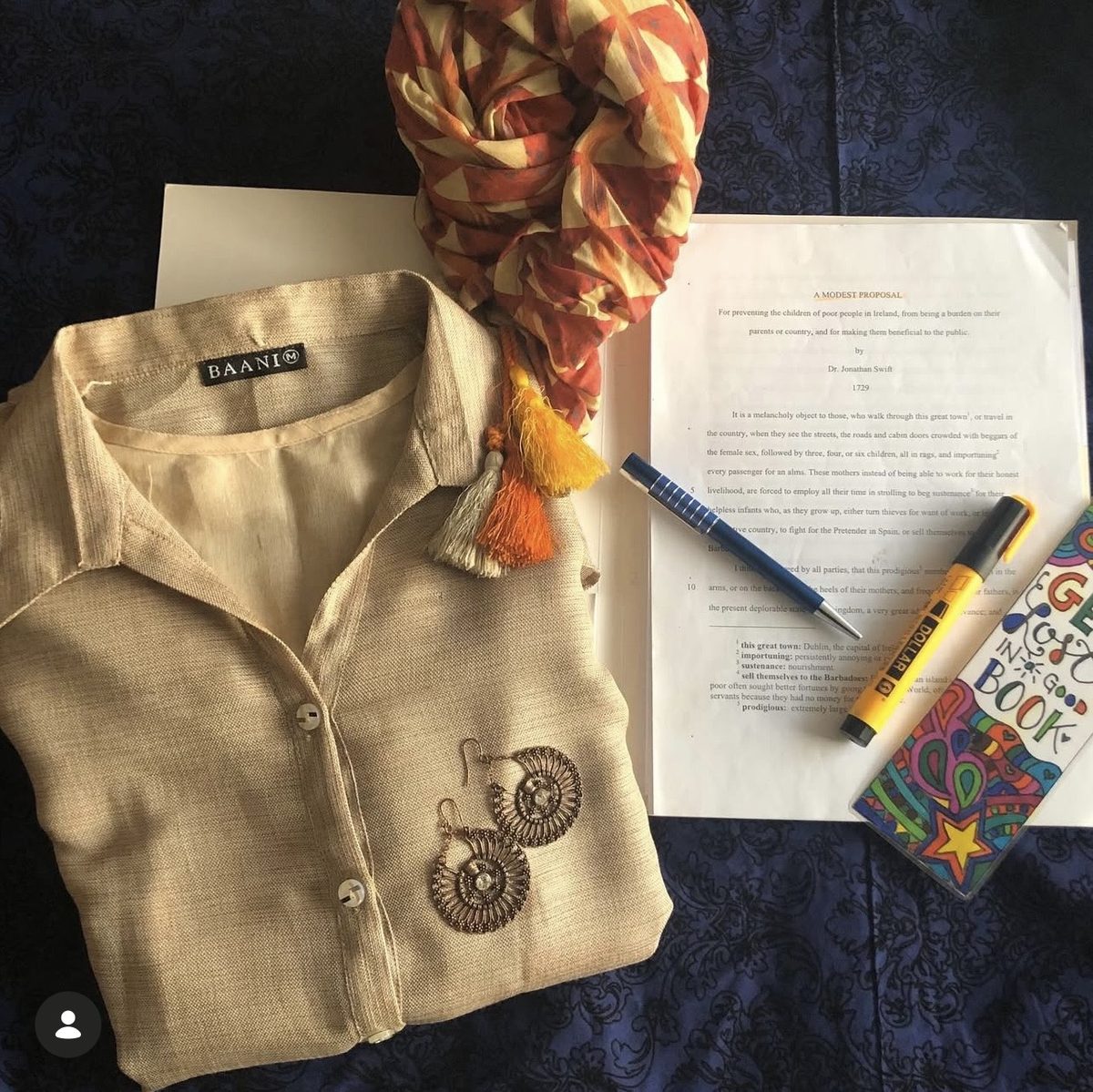 Baani product flatlay with neutral shirt, book and accessories